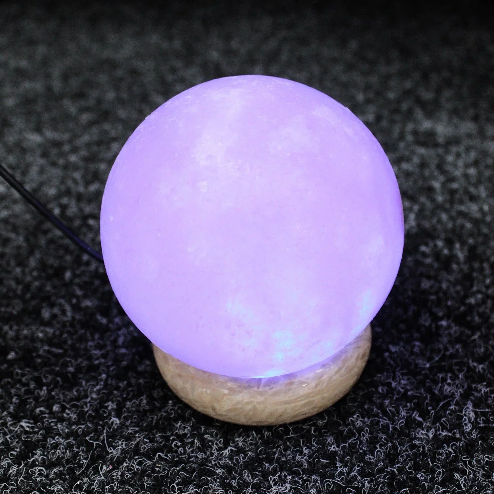 Purple glowing moon lamp on wooden base, ambient lighting decor on carpet