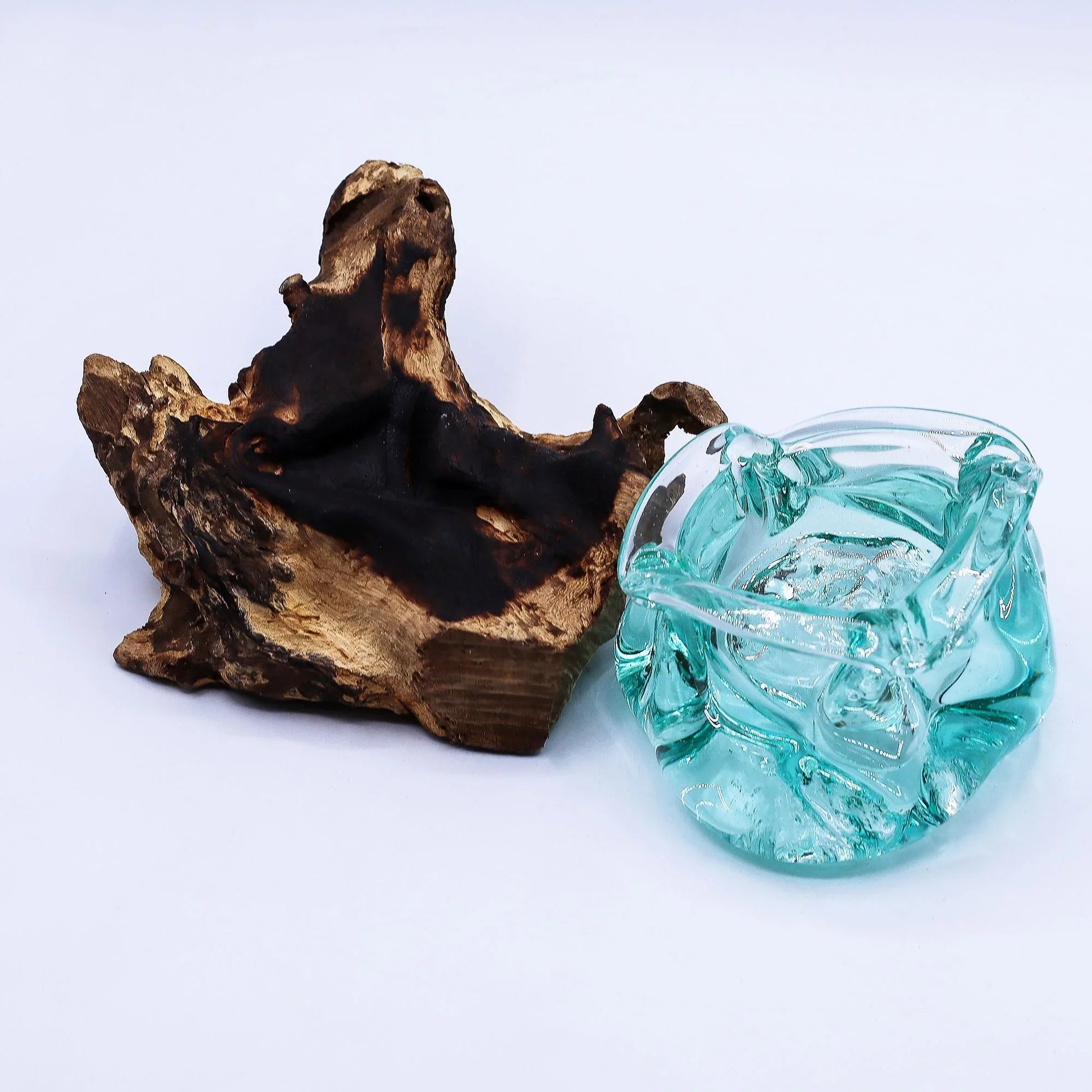 Decorative aqua glass bowl with rustic wood base on white background, home decor accessory